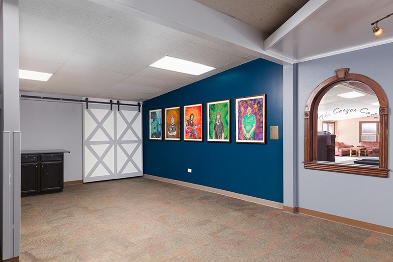 View of Shaunie Berry's portraits hanging on a blue wall.
